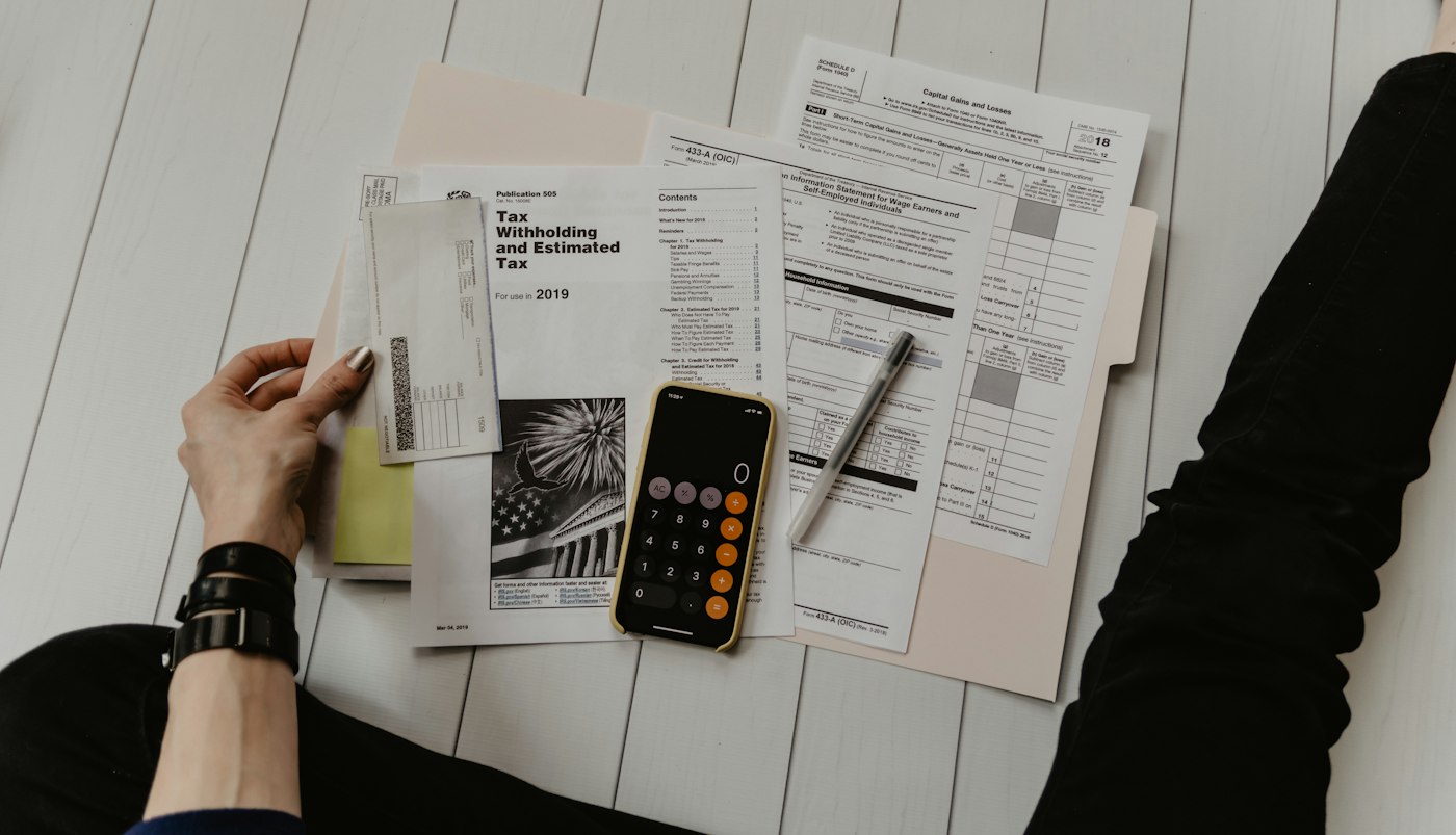 A close-up of a printed financial statement with a calculator and pen, the kind of filing the desk reads line by line before writing about an anomaly.